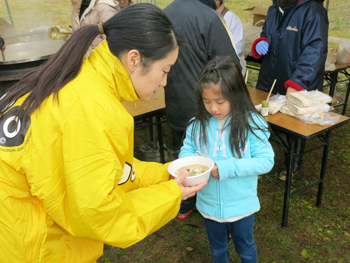 小学生にだご汁を渡す田中さん