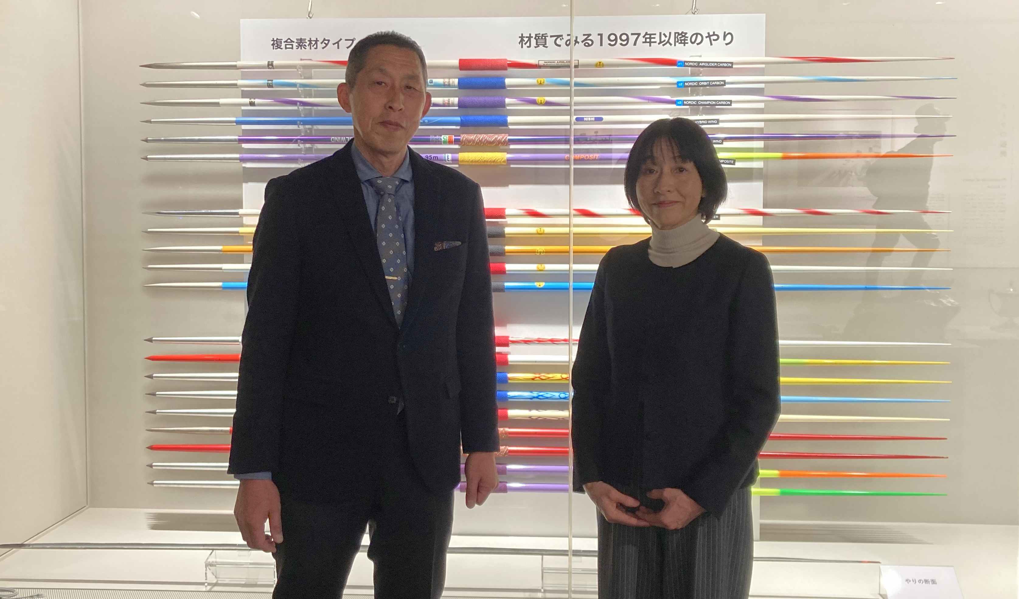 前田教授と須藤館長が並んで立っている写真。二人の後ろにはやりが展示されている。